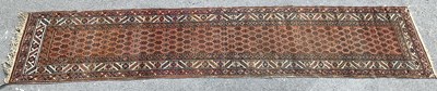 Lot 278 - A decorative Afgan runner on a red ground.