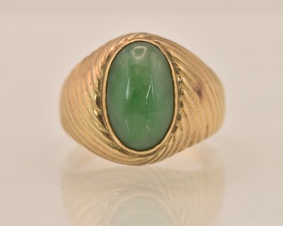 Lot 1263 - A 14K yellow gold oval cabochon green jade set...