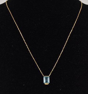 Lot 1405 - An 18ct yellow gold necklace, with a cut blue...