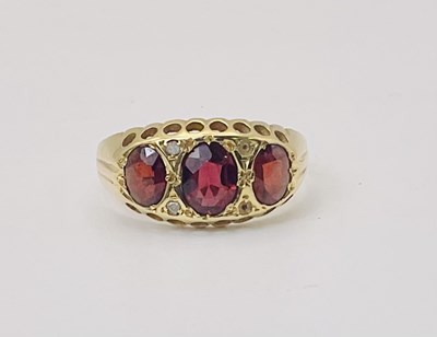 Lot 657 - A yellow metal garnet three stone ring, with...