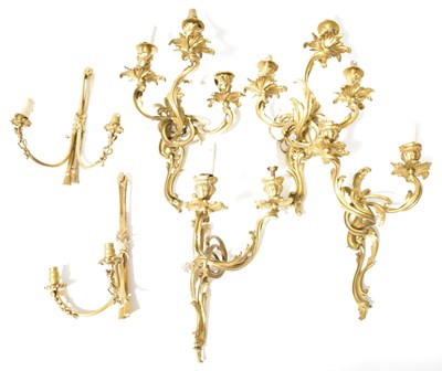 Lot 197 - Four Rococo-style gilt metal three-branch wall...