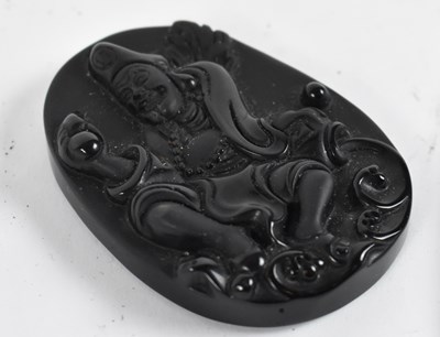 Lot 515 - A black stone cameo carved with smiling Buddha,...